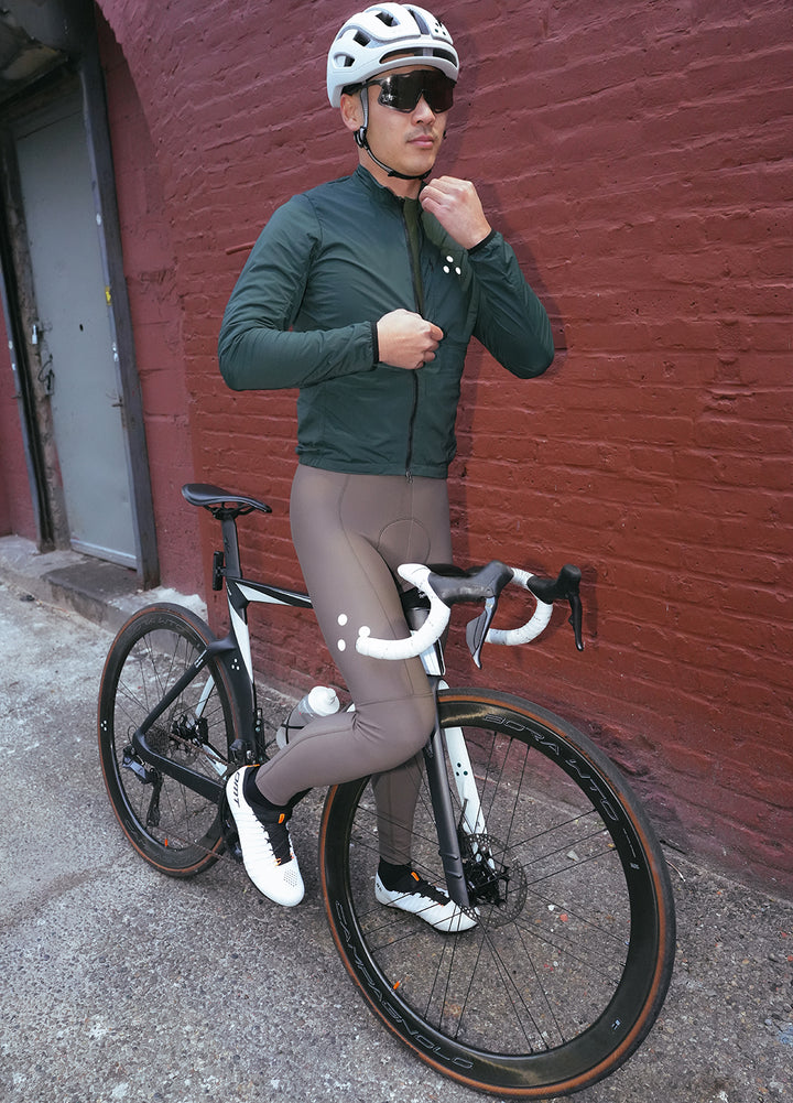 Person in DRS winter cycling gear with a bicycle against a red brick wall.