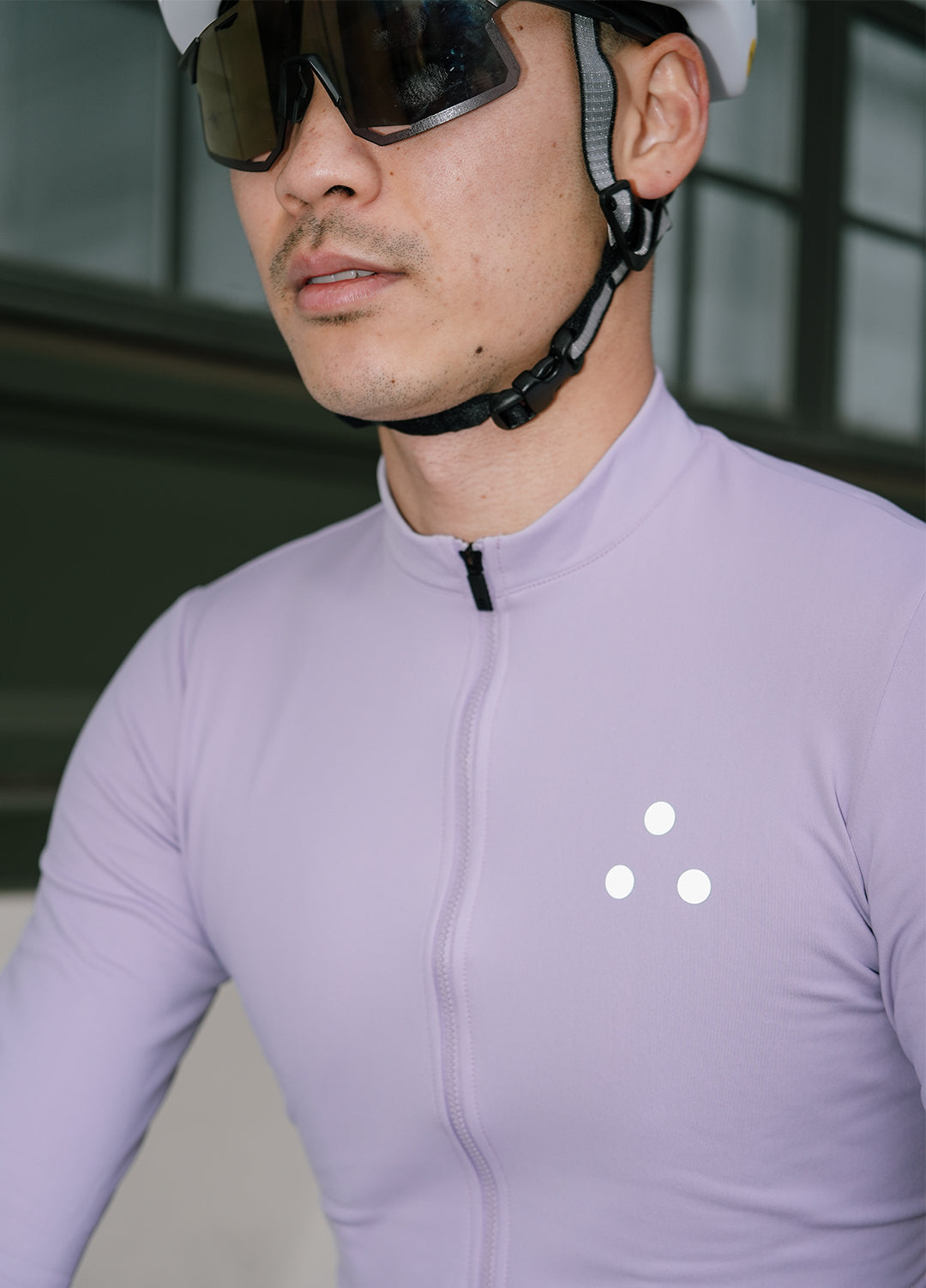 Person wearing a DRS light purple cycling jersey with a DRS brand logo, helmet, and sunglasses.