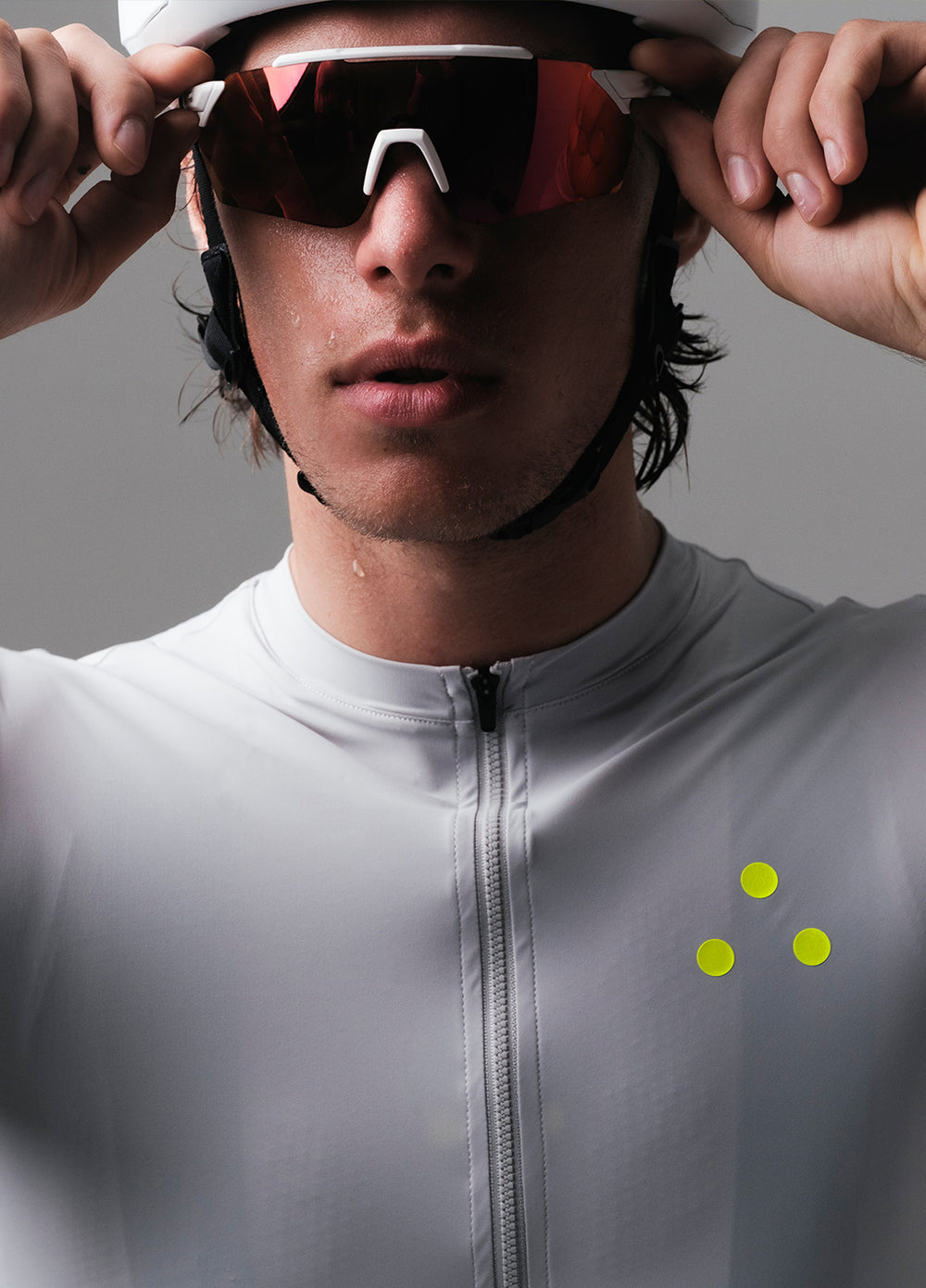 Person wearing a helmet and sunglasses wearing a DRS grey cycling jersey with a gray background