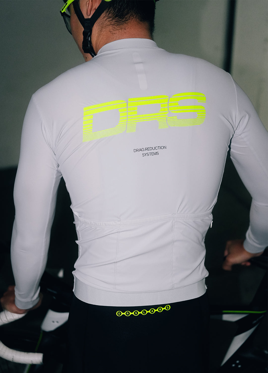 Person wearing a DRS light grey long-sleeve jersey with 'DRS' branding on the back.