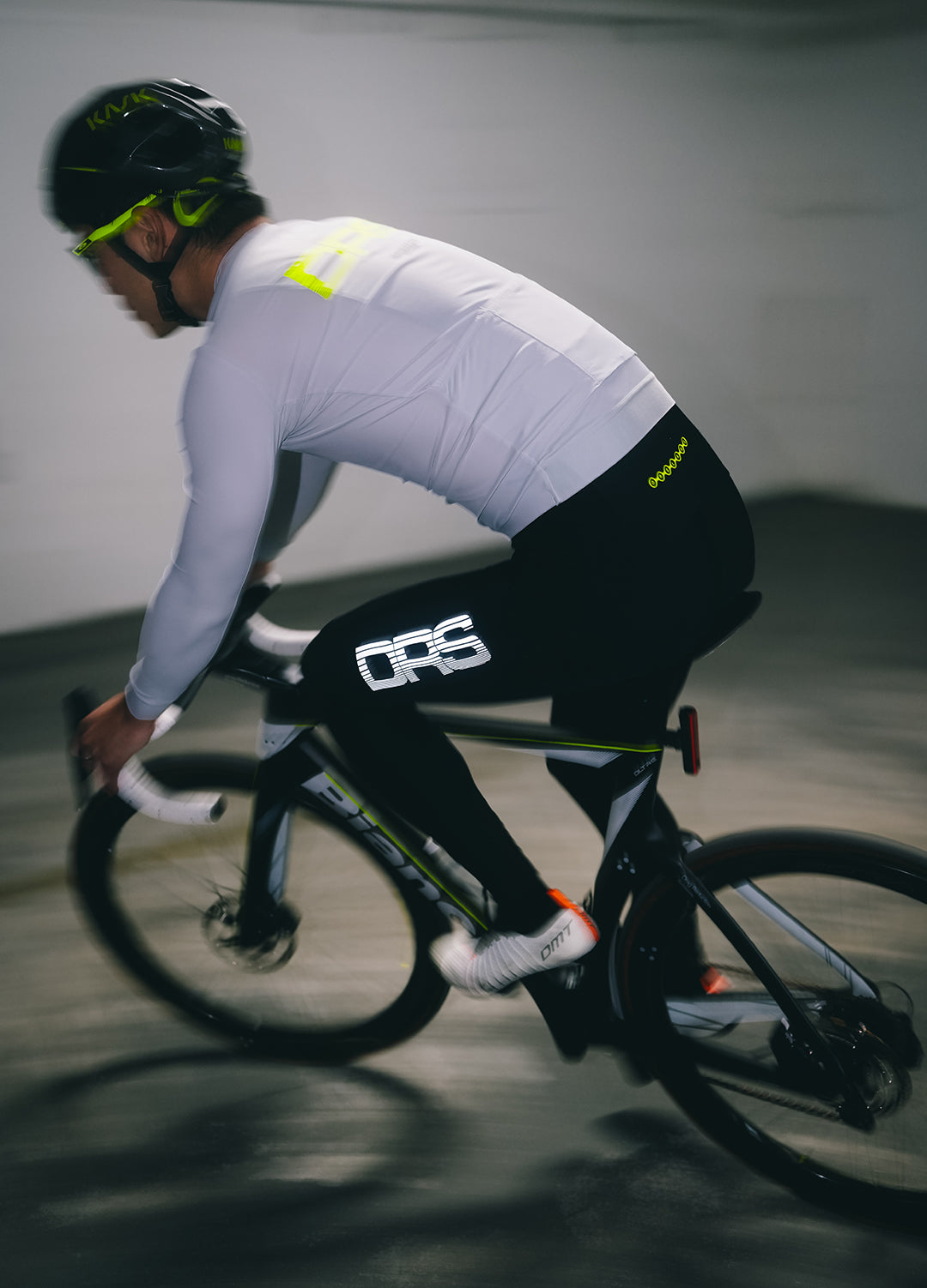Cyclist in a grey DRS long-sleeve jersey and black thermal bibs with 'DRS' logo riding a bicycle in new york. 