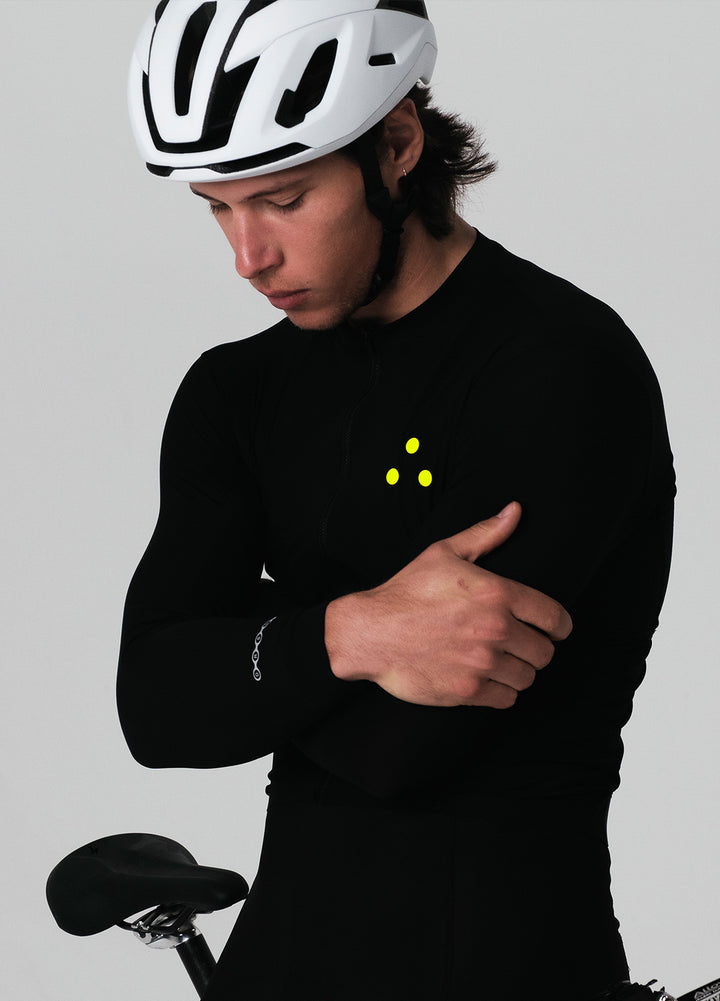 Person wearing a black DRS cycling kit with reflective elements on a gray background