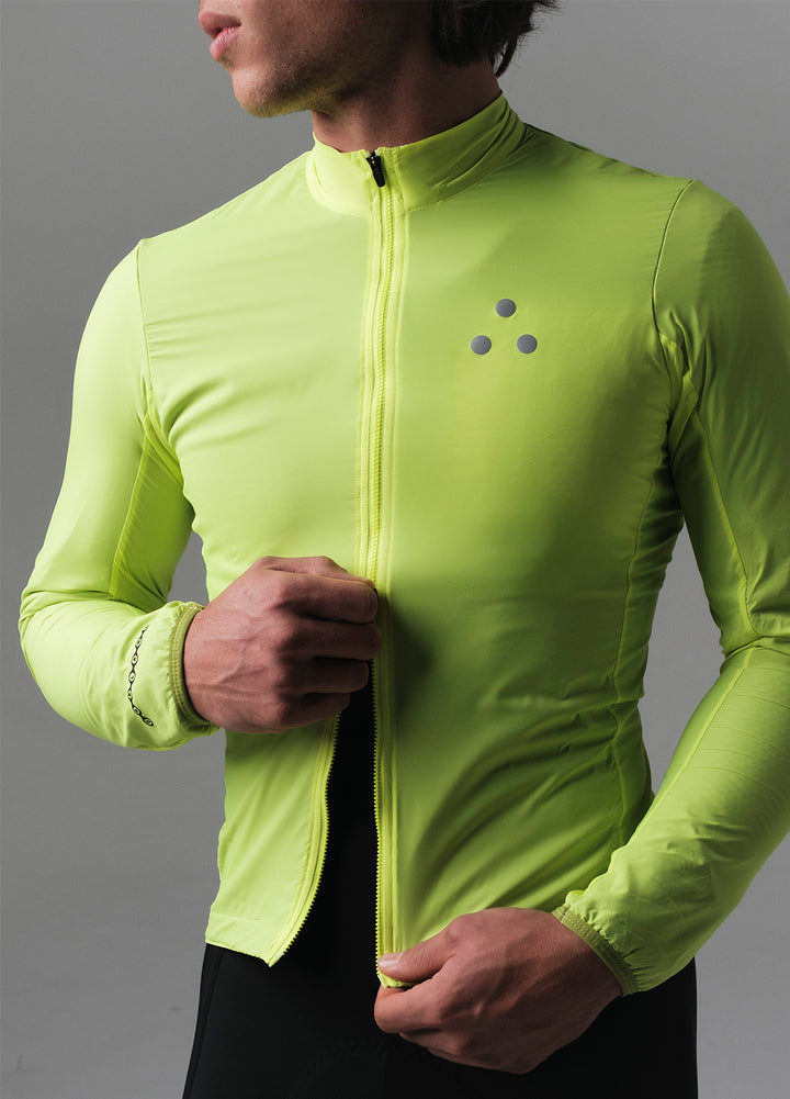 Person wearing a bright green DRS cycling  jacket with a logo on a gray background